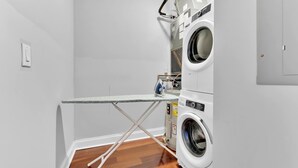 Ein Waschraum mit Waschmaschine, Trockner, Bügelbrett und Warmwasserbereiter.