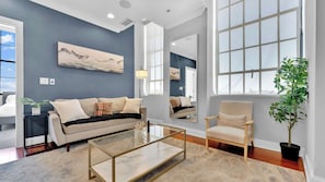 A modern living room with a sofa, armchair, coffee table, and large windows.