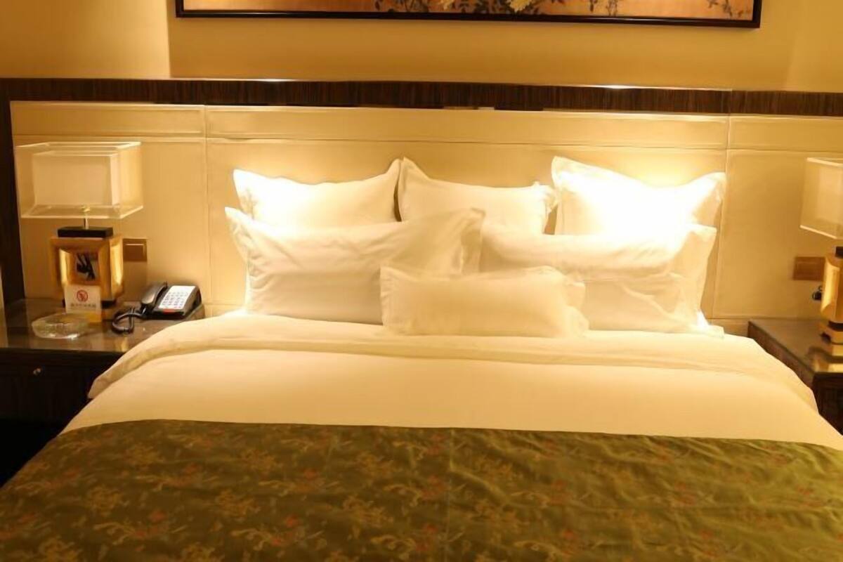 Une chambre d’hôtel avec un lit, un téléphone et une table de chevet avec une lampe.