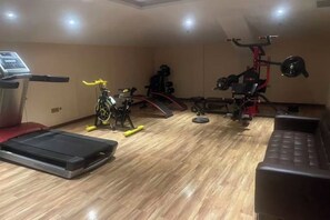 Une salle de sport équipée de matériel d’exercice, d’un tapis de course et d’un banc.