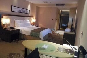 Una habitación de hotel con cama, mesita de noche, lámpara y una pequeña mesa con un tazón y una cuchara.
