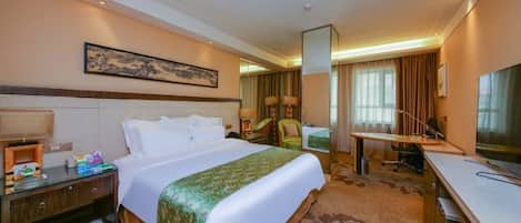 Una habitación de hotel con cama, escritorio, silla, televisor y baño.