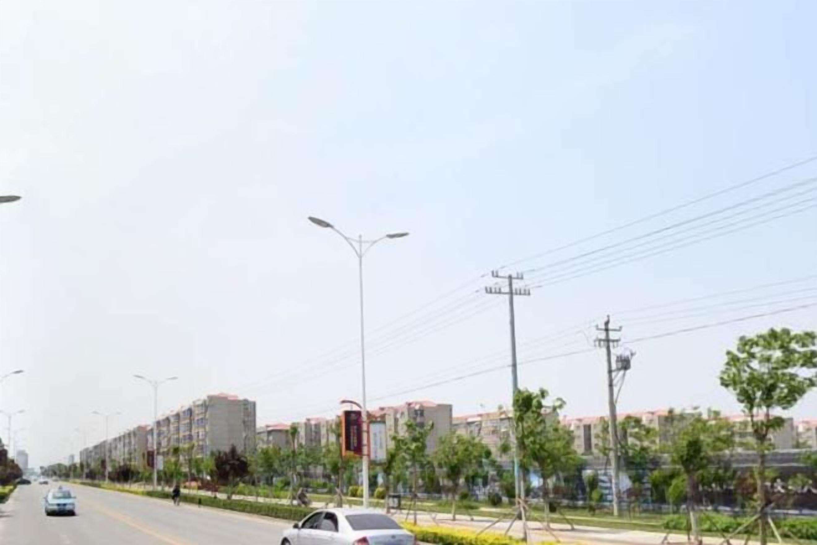 A street with buildings, cars, and streetlights.