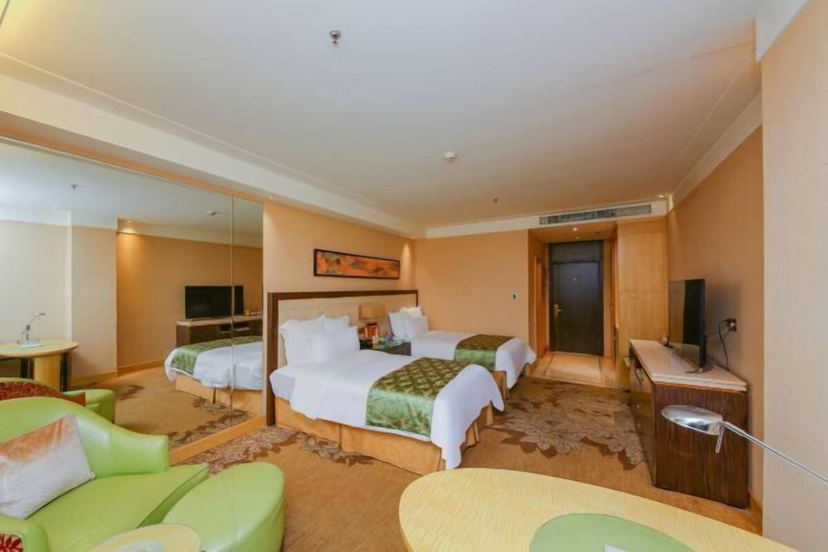 Une chambre d’hôtel avec deux lits, une télévision, un bureau et un miroir.