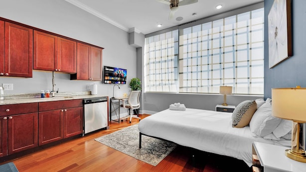 Una habitación de hotel moderna con cocina, un ventanal grande, una cama y un escritorio.