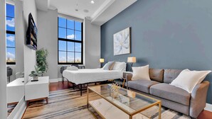 Una habitación de hotel moderna con cama, sofá y una mesa de centro de vidrio.
