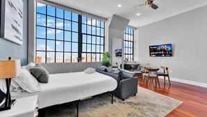 A modern bedroom with a bed, a sofa, a desk, and a TV.