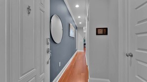 A hallway with a grey door, a white door, and a wall-mounted mirror. - Luxury Studio | Northern Libs | 1 Bed | Onsite gym (Philadelphia)