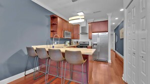 A modern kitchen with a central island, bar stools, stainless steel appliances, and wooden cabinetry. - Luxury Studio | Northern Libs | 1 Bed | Onsite gym (Philadelphia)