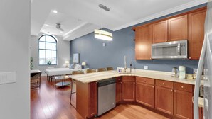 A modern kitchen with wooden cabinets, a stainless steel microwave, and a dishwasher. - Luxury Studio | Northern Libs | 1 Bed | Onsite gym (Philadelphia)