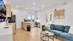 Un espacio habitable moderno con cocina, comedor y un amplio ventanal que ofrece vista a la ciudad.