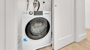 A front-loading washing machine in a room with a wooden floor and white walls.
