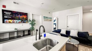 A modern kitchen with a large island, a built-in sink, and a flat-screen TV mounted above the island. - Cozy 2BD Apt | Fishtown | Gym (Philadelphia)
