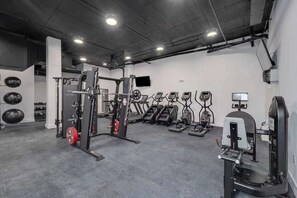 A gym with various exercise equipment including treadmills, elliptical machines, and weightlifting stations.