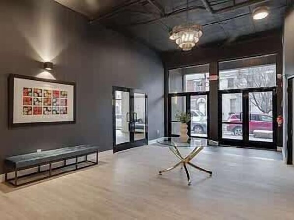 A modern interior with a bench, a chandelier, and large windows.