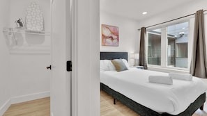 Una habitación de hotel moderna con una cama grande, una mesita de noche, una ventana con cortinas y vistas al exterior.