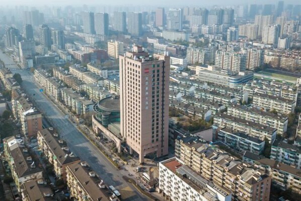A high-rise building with a central core, surrounded by a dense urban environment with multiple smaller buildings and a wide road. - Hangzhou Wenhua GINLAN JIA Grand Hotel (Hangzhou)