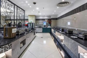 Una moderna hall d'albergo con una reception, un angolo per bevande self-service e una zona relax.