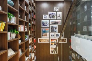 A narrow hallway with wooden bookshelves on one side and a wall with framed photographs on the other. - Hangzhou Wenhua GINLAN JIA Grand Hotel (Hangzhou)