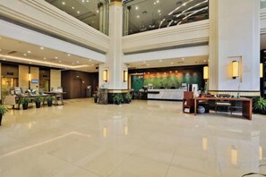 Eine großzügige Lobby mit einer Rezeption, einer Sitzecke und einer Säule.
