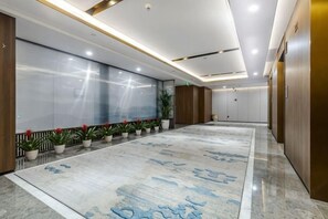 Eine geräumige Lobby mit einer langen Rezeption, Topfpflanzen und einem gemusterten Teppich.