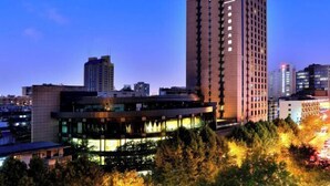 A high-rise building with a modern architectural design, surrounded by other buildings and trees. - Hangzhou Wenhua GINLAN JIA Grand Hotel (Hangzhou)