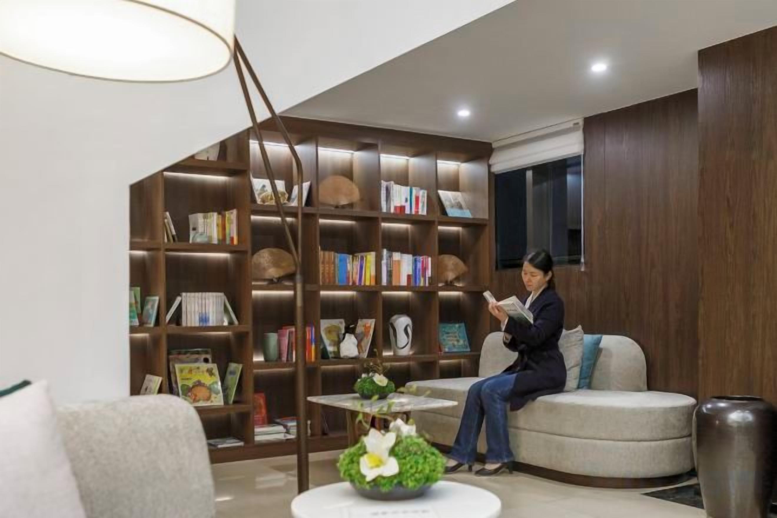 Um interior moderno com uma grande estante de livros, uma área de estar circular e uma planta decorativa.
