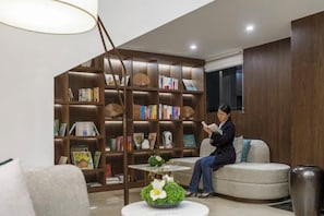Un interior moderno con una gran estantería, una zona de estar circular y una planta decorativa.