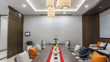 A conference room with a long table, chairs, and a projector screen.
