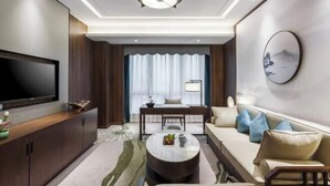 A modern living room with a flat-screen TV, a sofa, a coffee table, and a dining area with a table and chairs. - Hangzhou Wenhua GINLAN JIA Grand Hotel (Hangzhou)