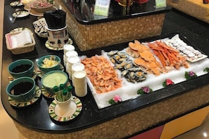 A buffet with seafood, including shrimp and mussels, and various condiments.