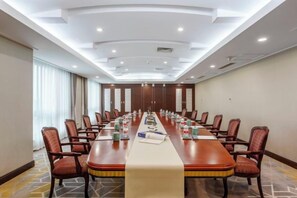 Una sala conferenze con un lungo tavolo, sedie e pavimento rivestito di moquette.
