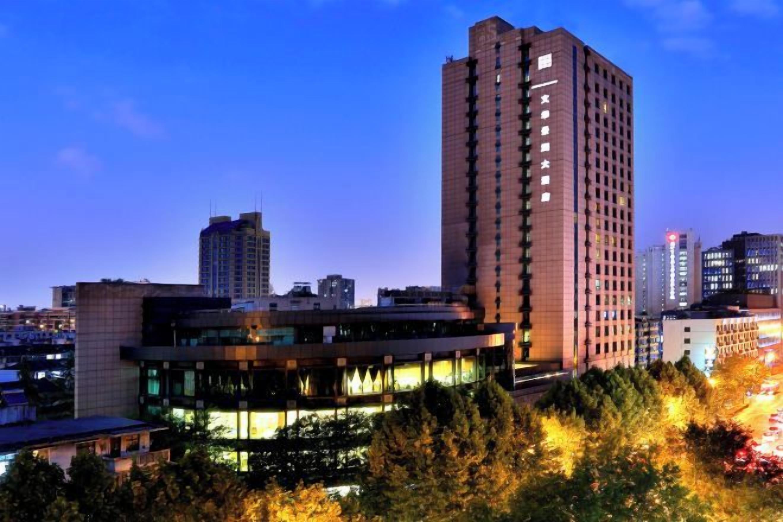 A high-rise building with a modern design, surrounded by other buildings and trees.