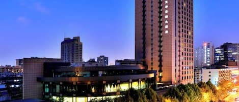 A high-rise building with a modern design, surrounded by other buildings and trees.