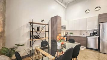 A modern kitchen with stainless steel appliances, a glass dining table, and black chairs.