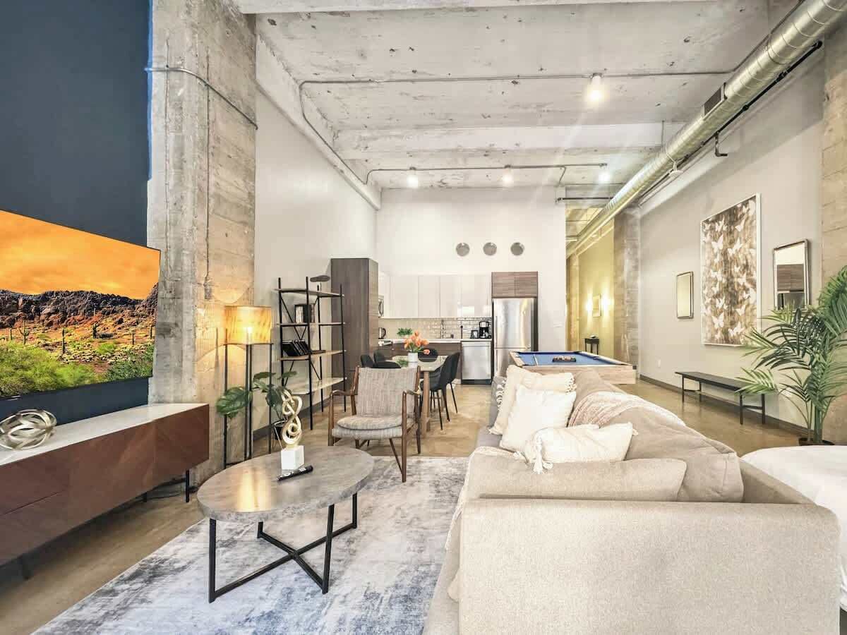 A modern living room with a sofa, coffee table, and a dining area with chairs and a table.