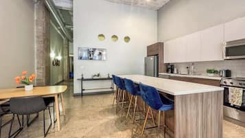 A modern kitchen with a central island, bar stools, and a dining area with a table and chairs.