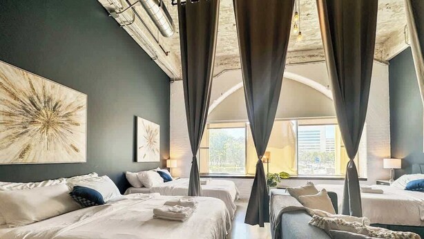A hotel room with two beds, a sofa, and a large window with curtains. - Elegant 2BD | DT Dallas | Sleeps 10 | ValetParking (Dallas)