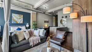 Un salon moderne avec un canapé gris, une table basse agrémentée d’un objet décoratif et un mur d’accent en bois.