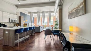 Une cuisine moderne dotée d’un îlot central, de tabourets de bar et d’un coin repas avec une table et des chaises.