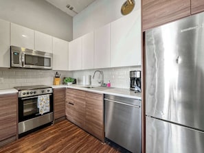 Una cocina moderna con electrodomésticos de acero inoxidable, armarios de madera y salpicadero de azulejos.