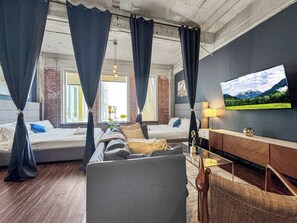 A modern bedroom with a bed, a sofa, a TV, and a lamp.