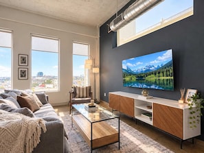 A modern living room with a sofa, coffee table, TV, and a city view.
