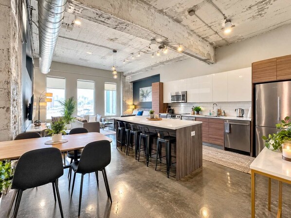 A modern kitchen with a central island, bar stools, and stainless steel appliances.