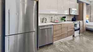 A modern kitchen with stainless steel appliances, wooden cabinets, and a tiled backsplash.