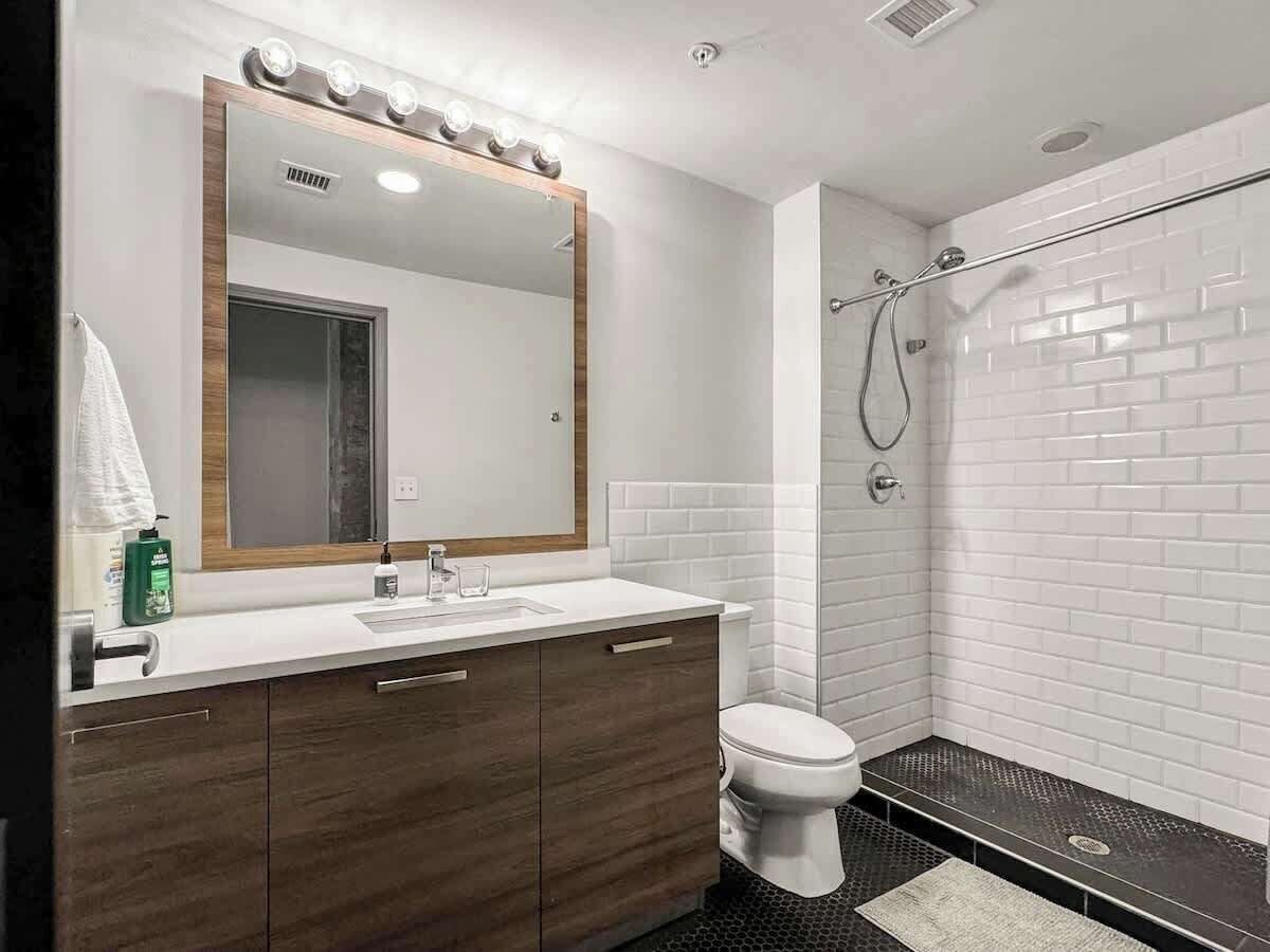 Un baño moderno con tocador, lavamanos, espejo y ducha.