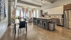 A spacious kitchen with stainless steel appliances, a central island with stools, and a dining area with a table and chairs.