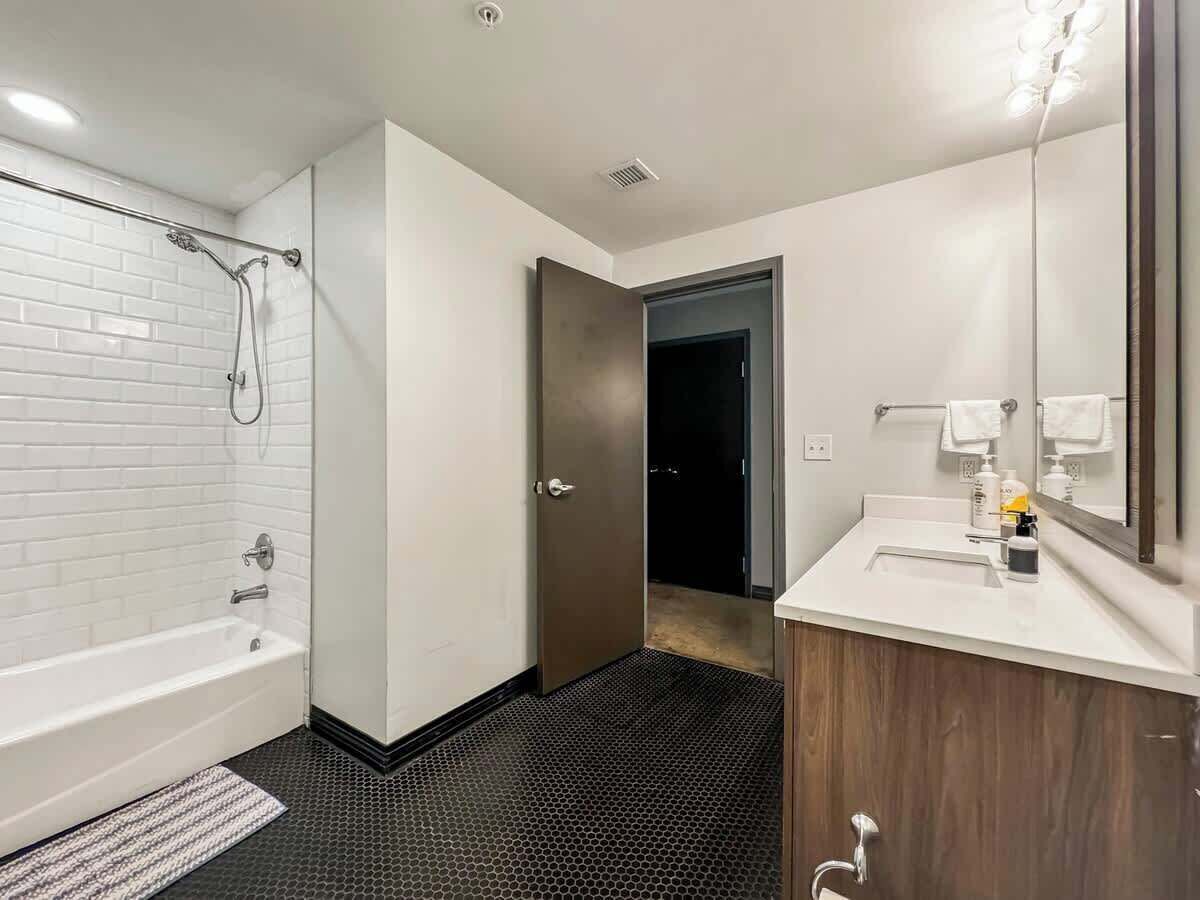 A modern bathroom with a white bathtub, a shower area, and a vanity with a mirror.