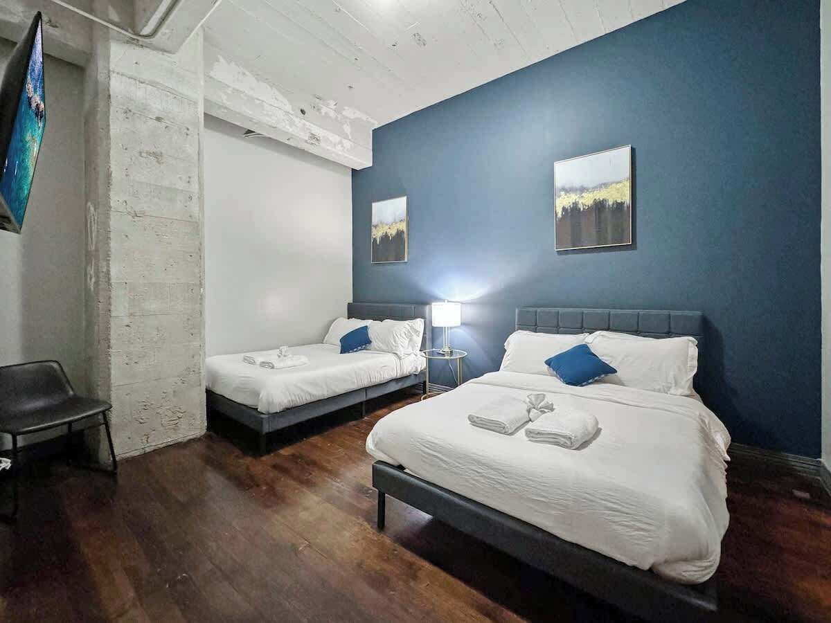 A hotel room with two beds, a chair, and artwork on the walls.