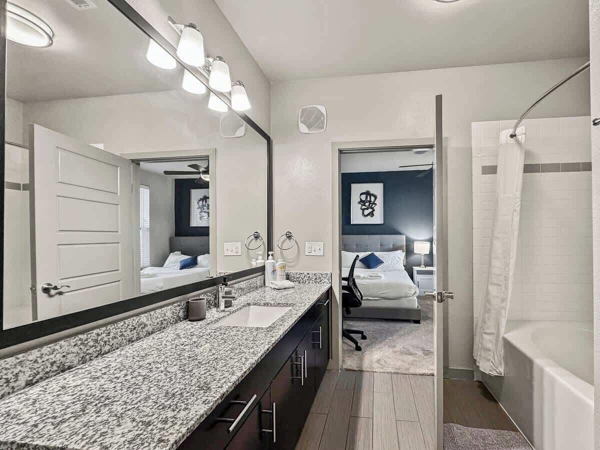 Un baño moderno con un espejo grande, un lavabo y una zona de ducha.